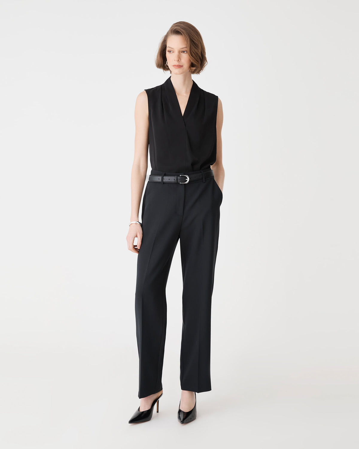 Alivia 2 V-Neck Top in black, front view, tucked into black trousers with a belt