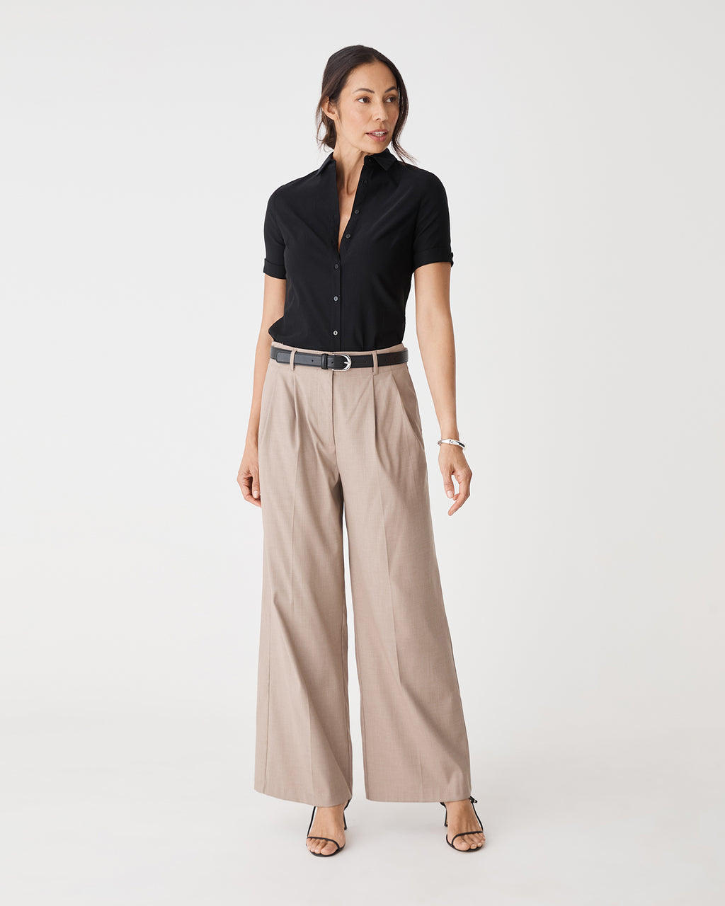 Full-length front view of the black Morgan Short Sleeve Cuff Shirt worn with beige wide-leg pants