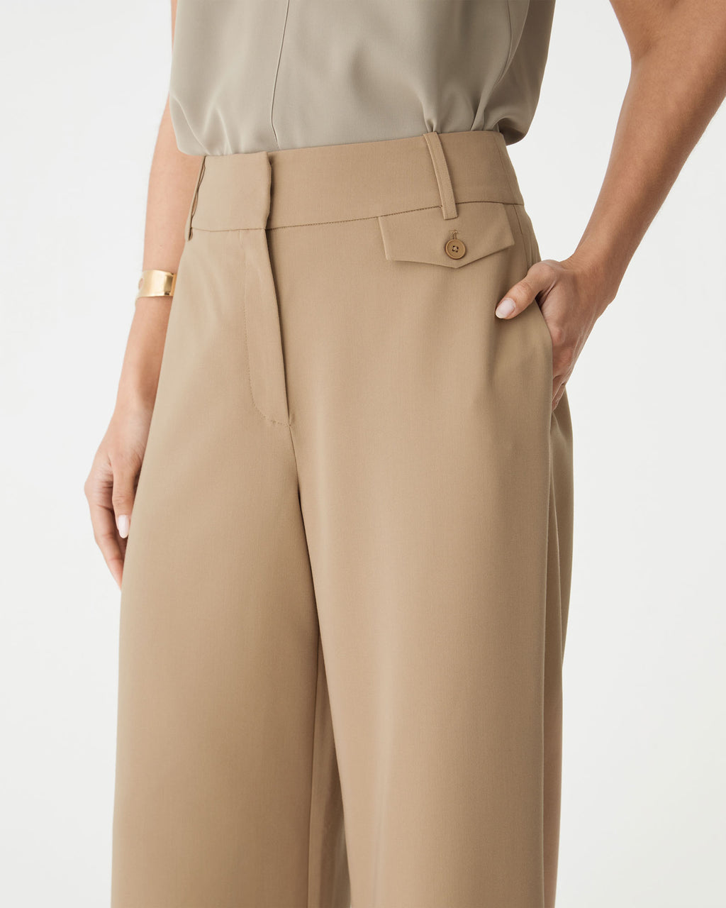 Detail of the pocket flap and button on the camel pants at the hip