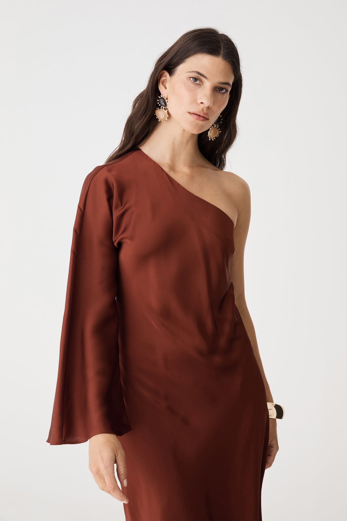 Close-up of the asymmetrical one-shoulder neckline and flared sleeve in brick satin