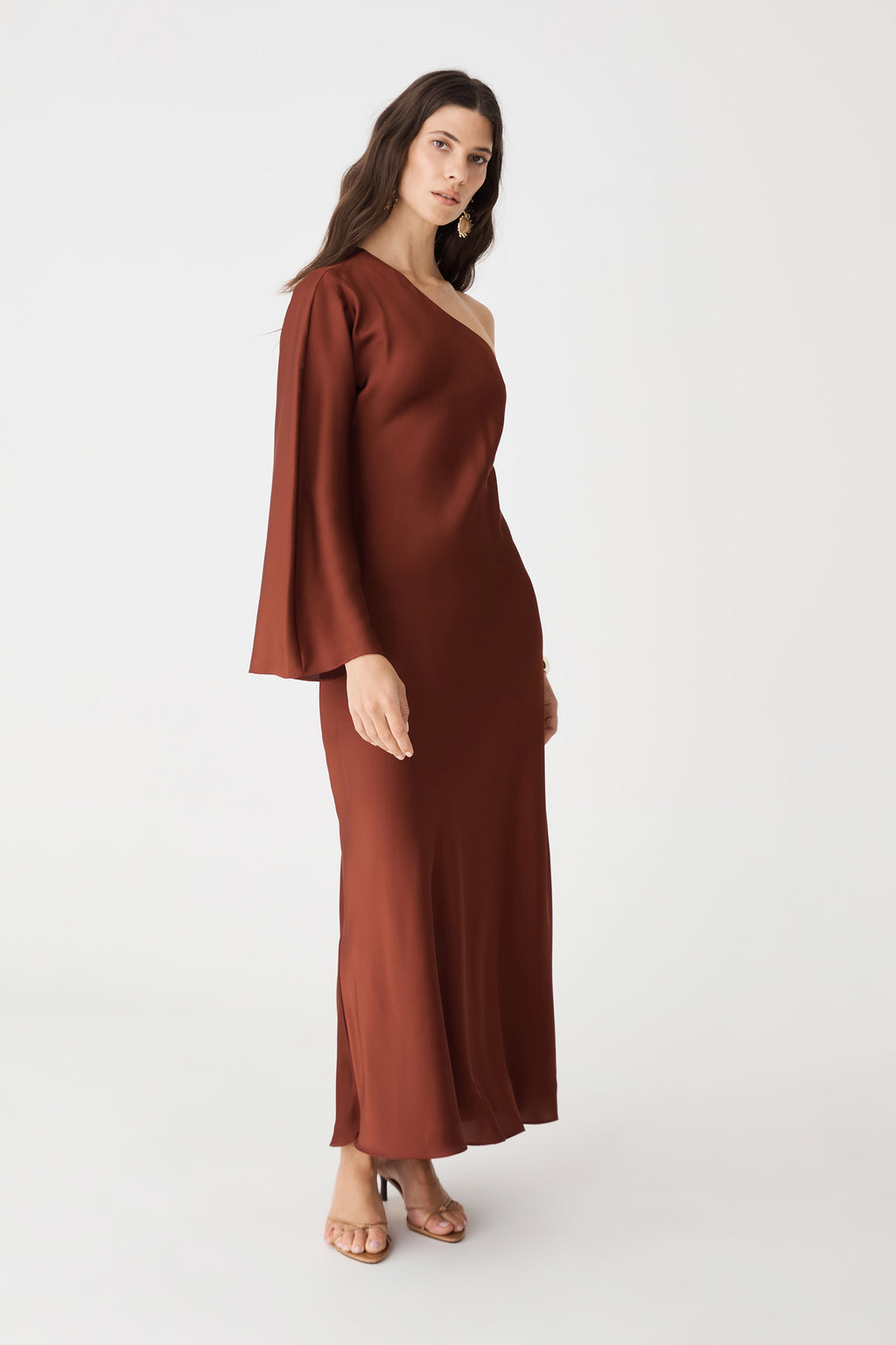 Side view showing fluid drape of the brick satin maxi dress, worn with heeled sandals