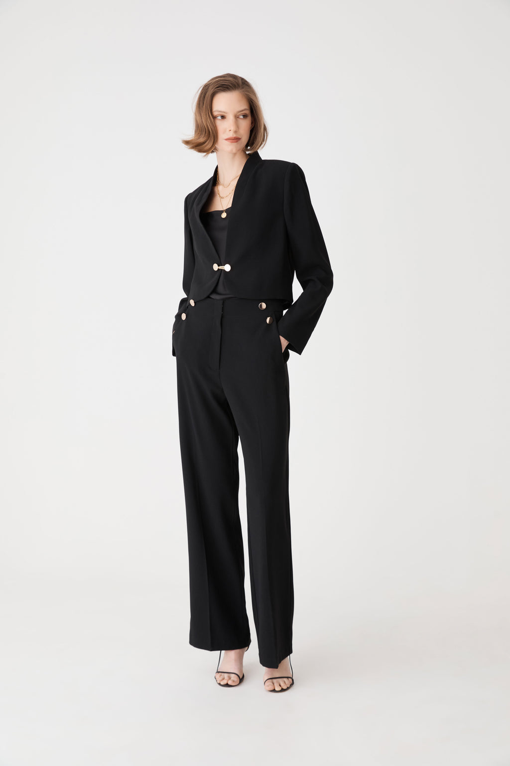 Full-length front view of the black cropped jacket worn open over matching black trousers