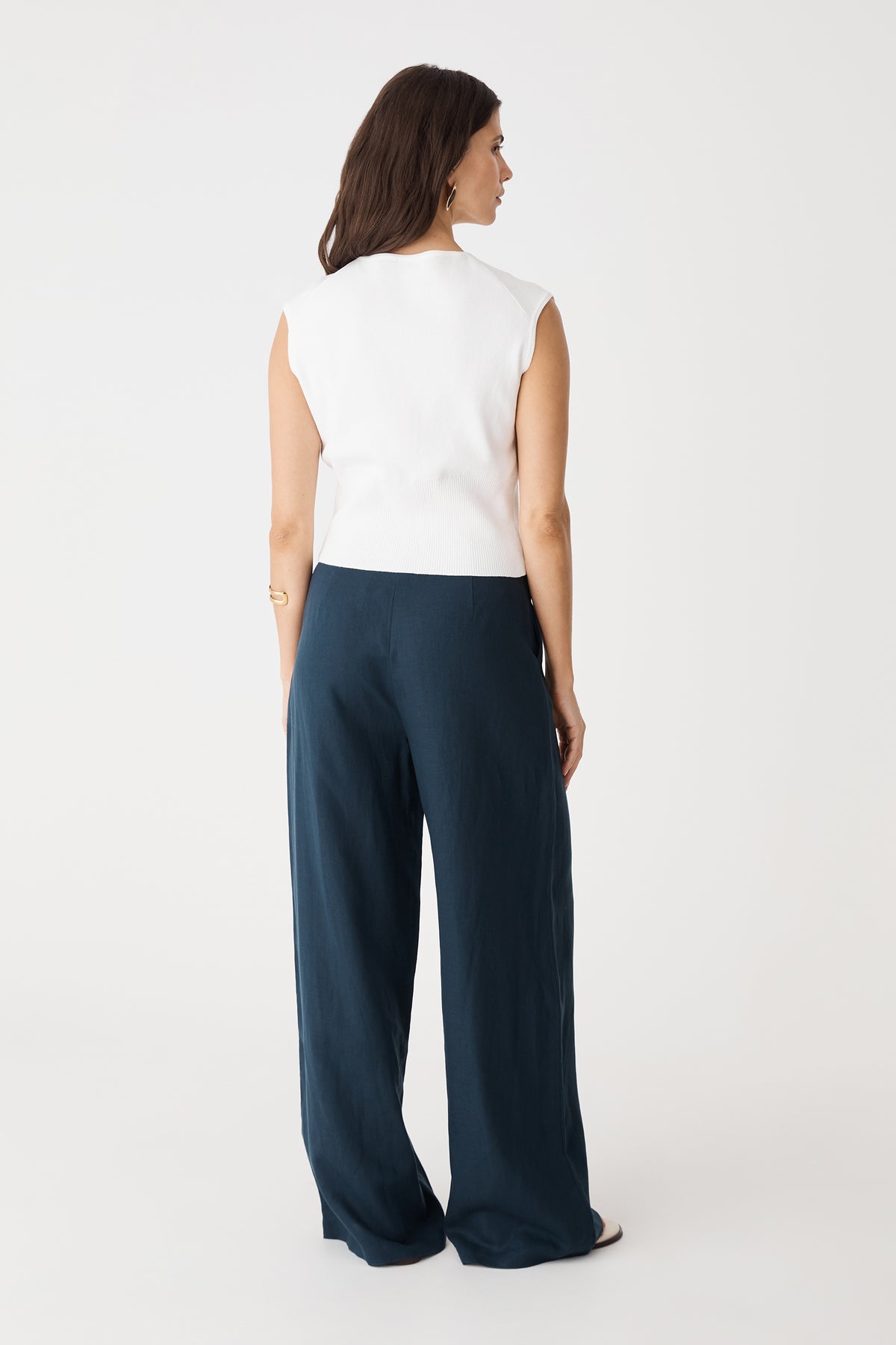 Back view of the ivory Faye Sleeveless Button Up Knit with navy wide-leg trousers