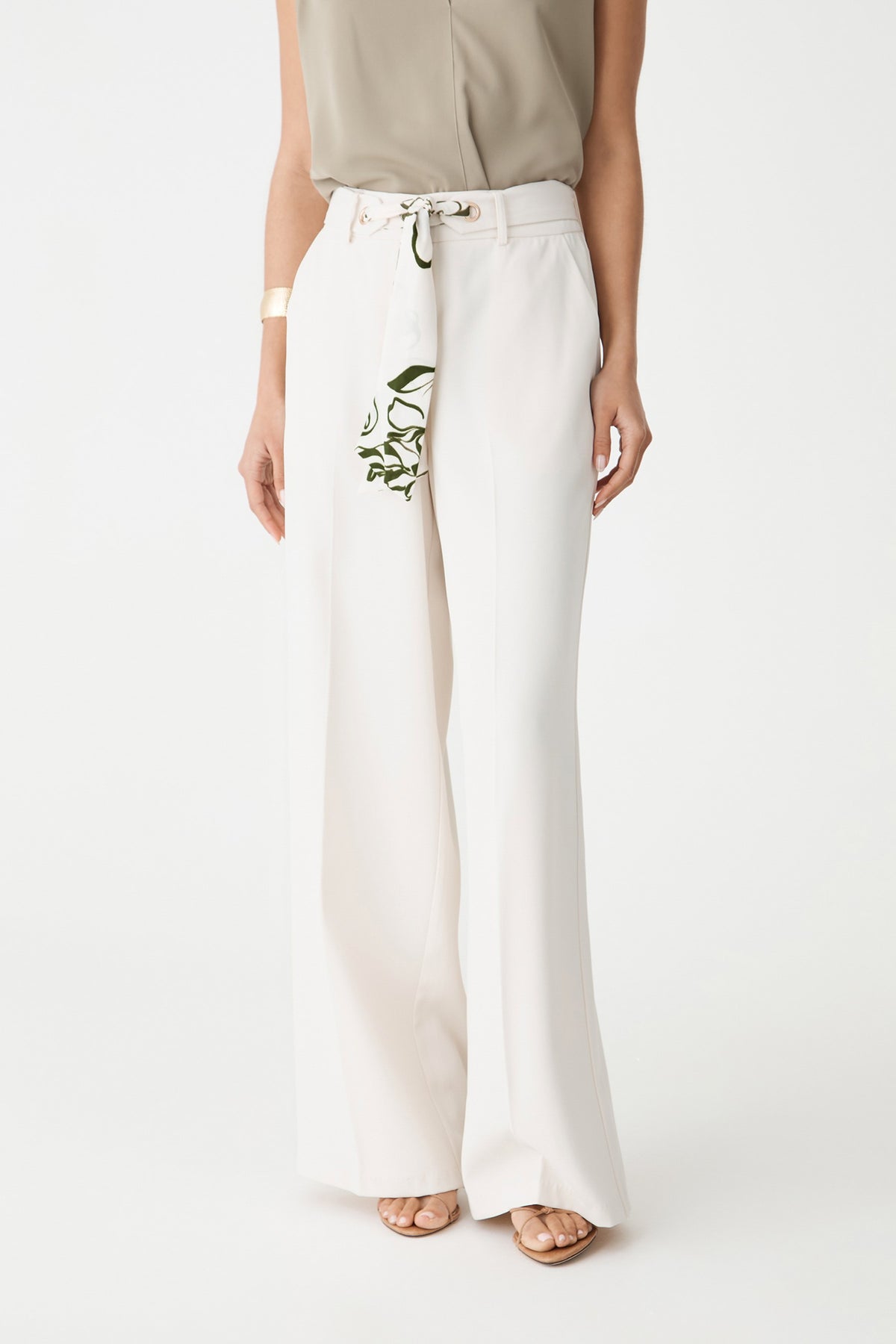Close-up of the cream wide-leg pants, showing the scarf belt threaded through gold-tone eyelets