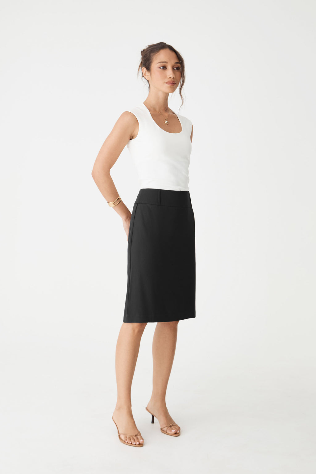 Side view of the Veronica Straight Crepe Skirt in black, worn with a white sleeveless top