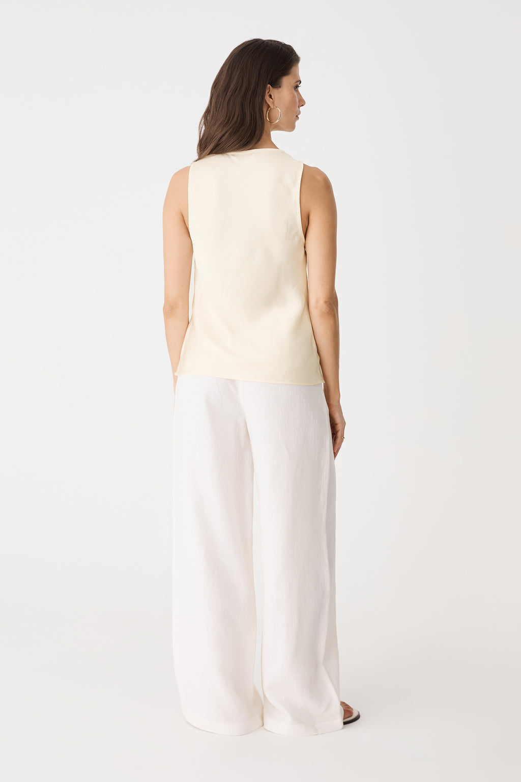 Back view of the sleeveless champagne satin top with white trousers