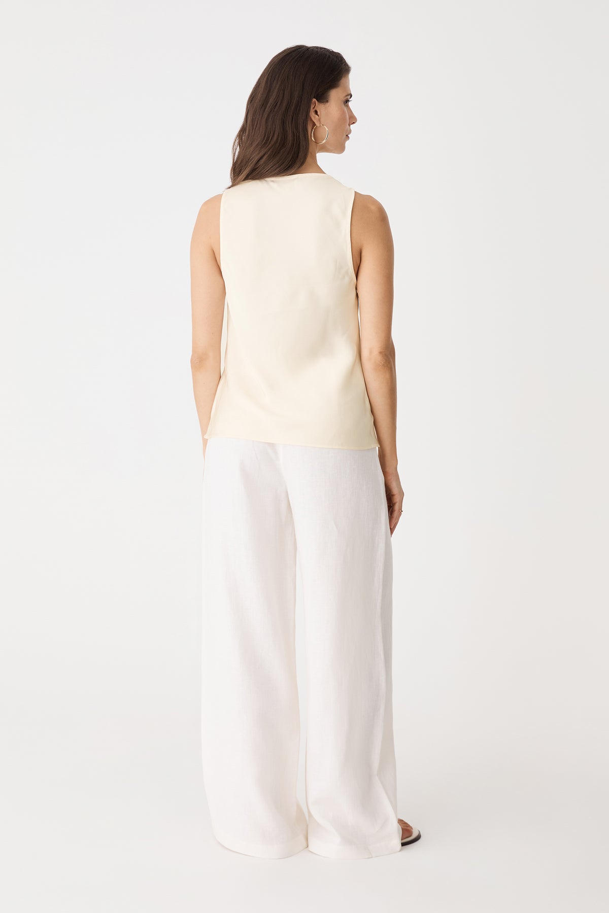 Back view of the sleeveless champagne satin top with white trousers
