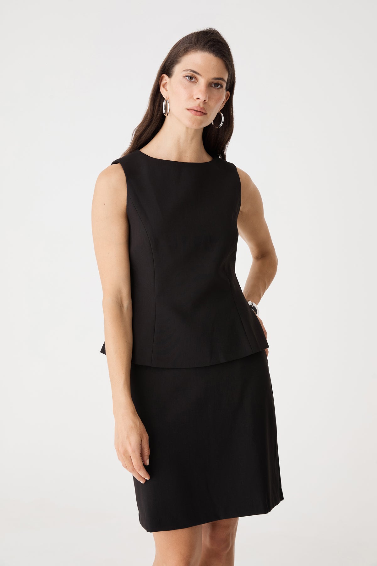 Front close view of the black Melanie 2 Tailored Top showing boat neckline and peplum hem