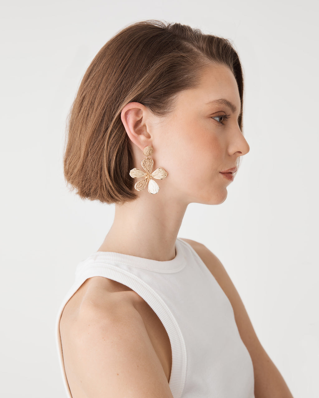 Zaria Bloom Drop Earrings in beige raffia with gold-tone edging, worn, side view
